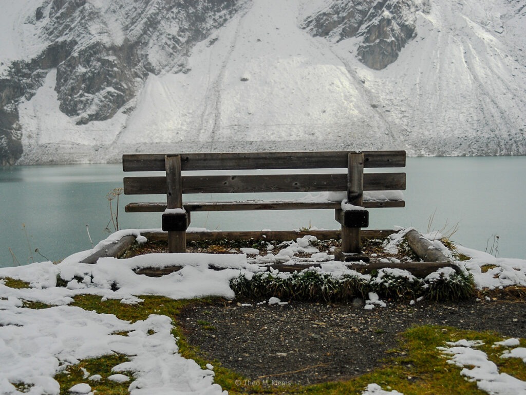 verschneite Bank am Mooserboden mit Blick auf den Stausee in Kaprun
