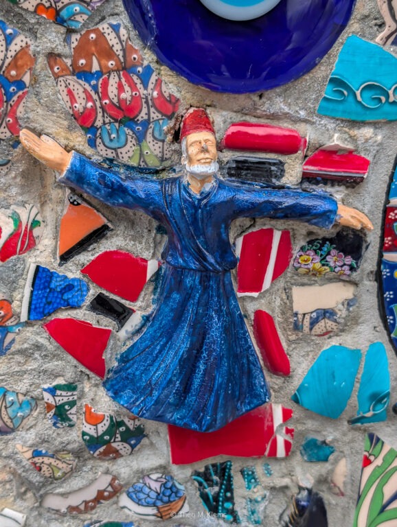 Figur eines tanzenden Derwischs vor farbigem Mosaikhintergrund in Istanbul