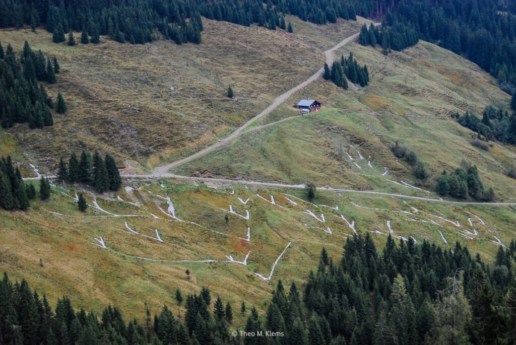 Berghang mit sichtbaren Wanderwegen und Linien im Gelände oberhalb einer Alm